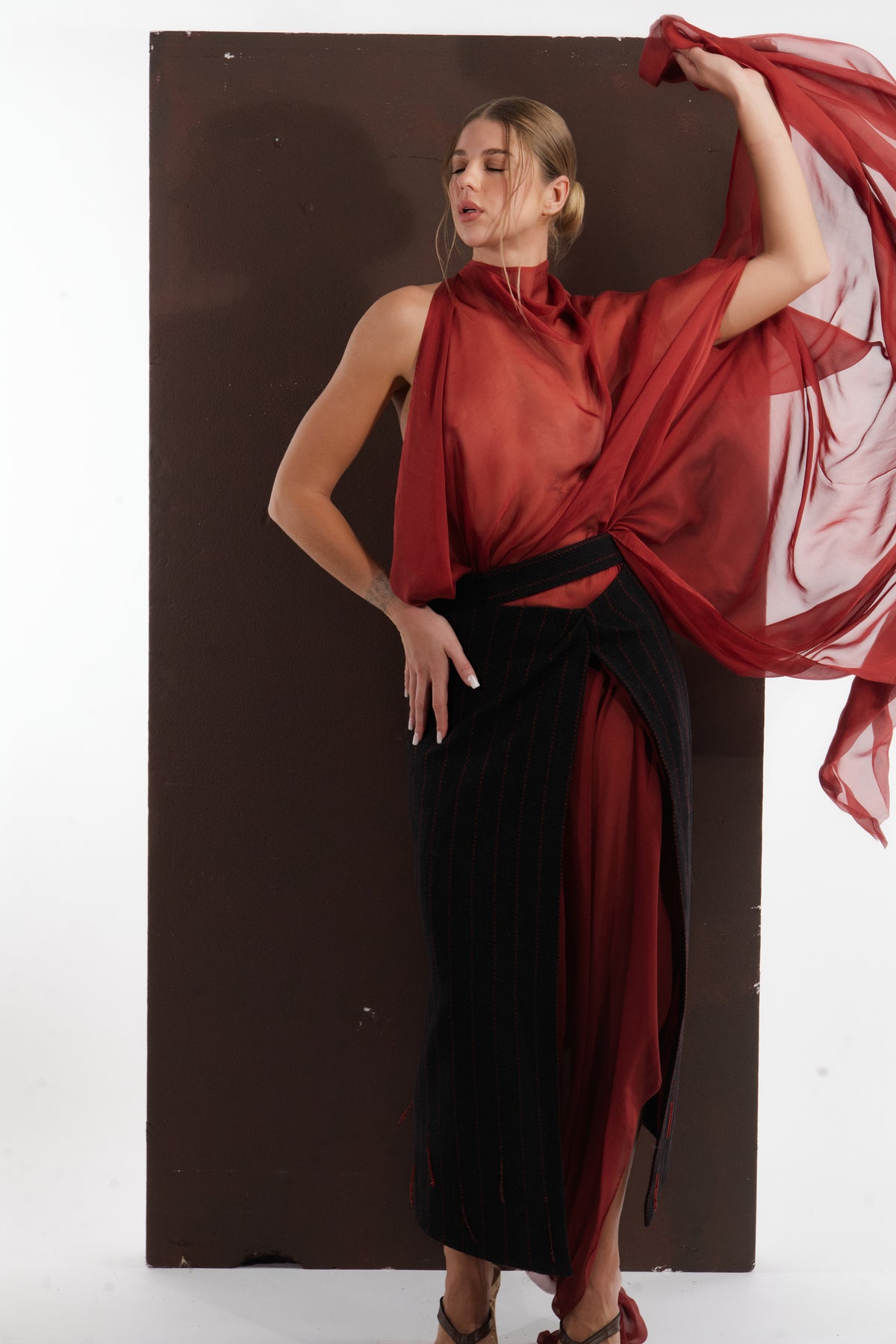ALISADUDAJ red silk and black pinstripe wool set, front view with arm raised holding the silk panel, silk and wool