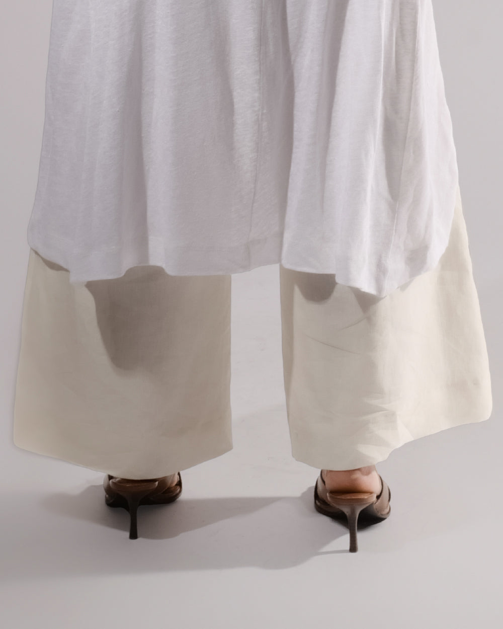 ALISADUDAJ cream linen wide-leg trousers, close-up of hem and heeled sandals, linen