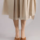 ALISADUDAJ beige linen and viscose one-shoulder draped dress, close-up of culotte hem and sandals