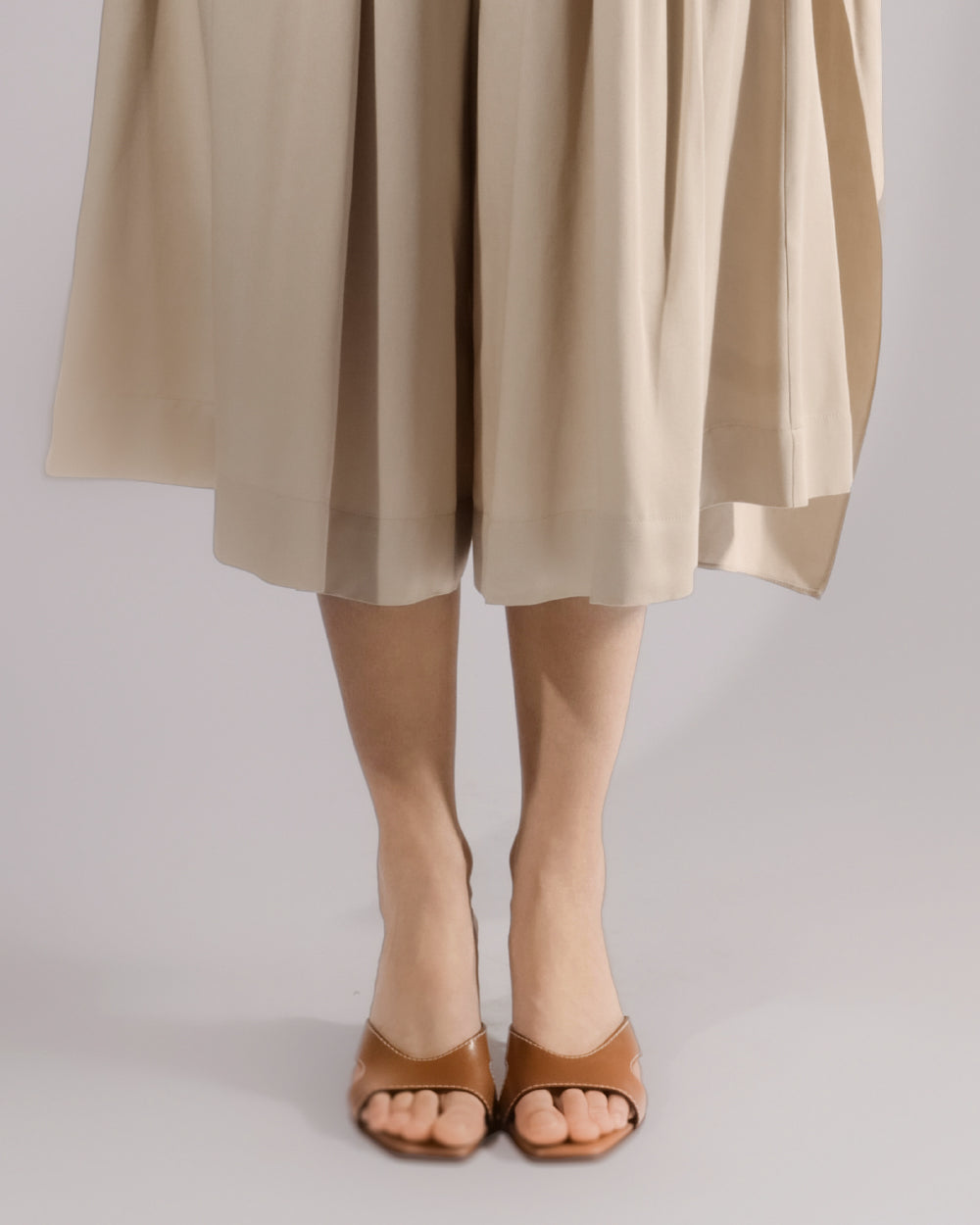 ALISADUDAJ beige linen and viscose one-shoulder draped dress, close-up of culotte hem and sandals