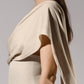 ALISADUDAJ beige linen and viscose one-shoulder draped dress, side close-up of draped sleeve and waist seam, linen and viscose