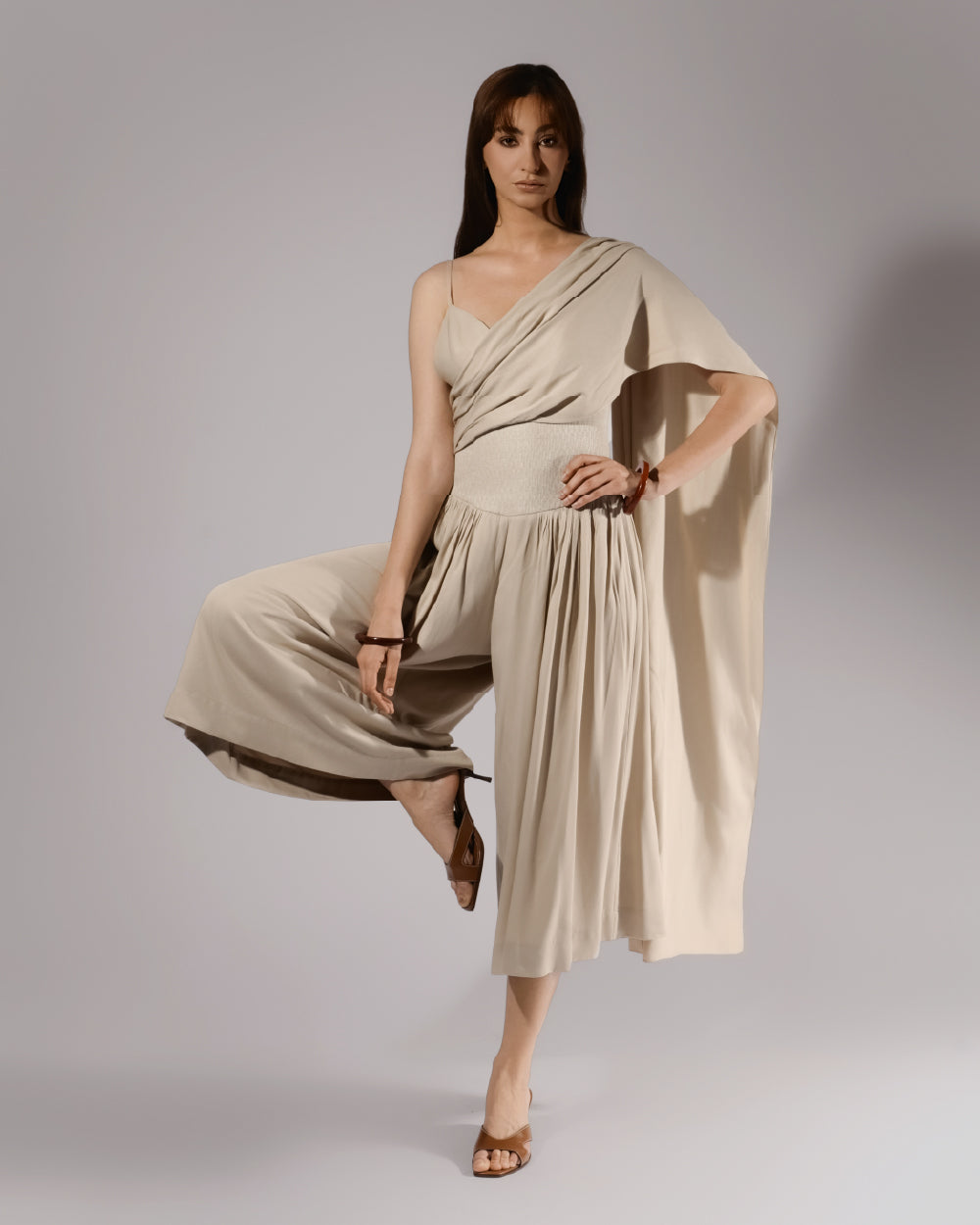 ALISADUDAJ beige linen and viscose one-shoulder draped dress, three-quarter view in movement showing skirt volume