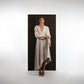 ALISADUDAJ beige wool asymmetric dress, front view with hand at waist showing bishop sleeves and asymmetric hem