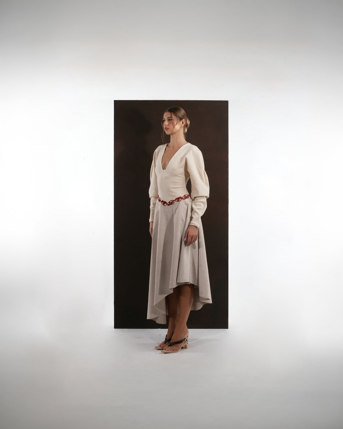 ALISADUDAJ beige wool asymmetric dress, side profile showing sleeve volume and asymmetric hem