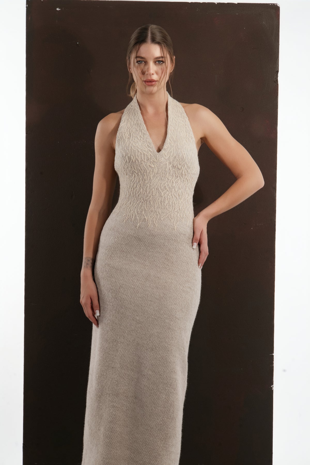 ALISADUDAJ beige wool halterneck column dress, three-quarter view with hand on hip, half length