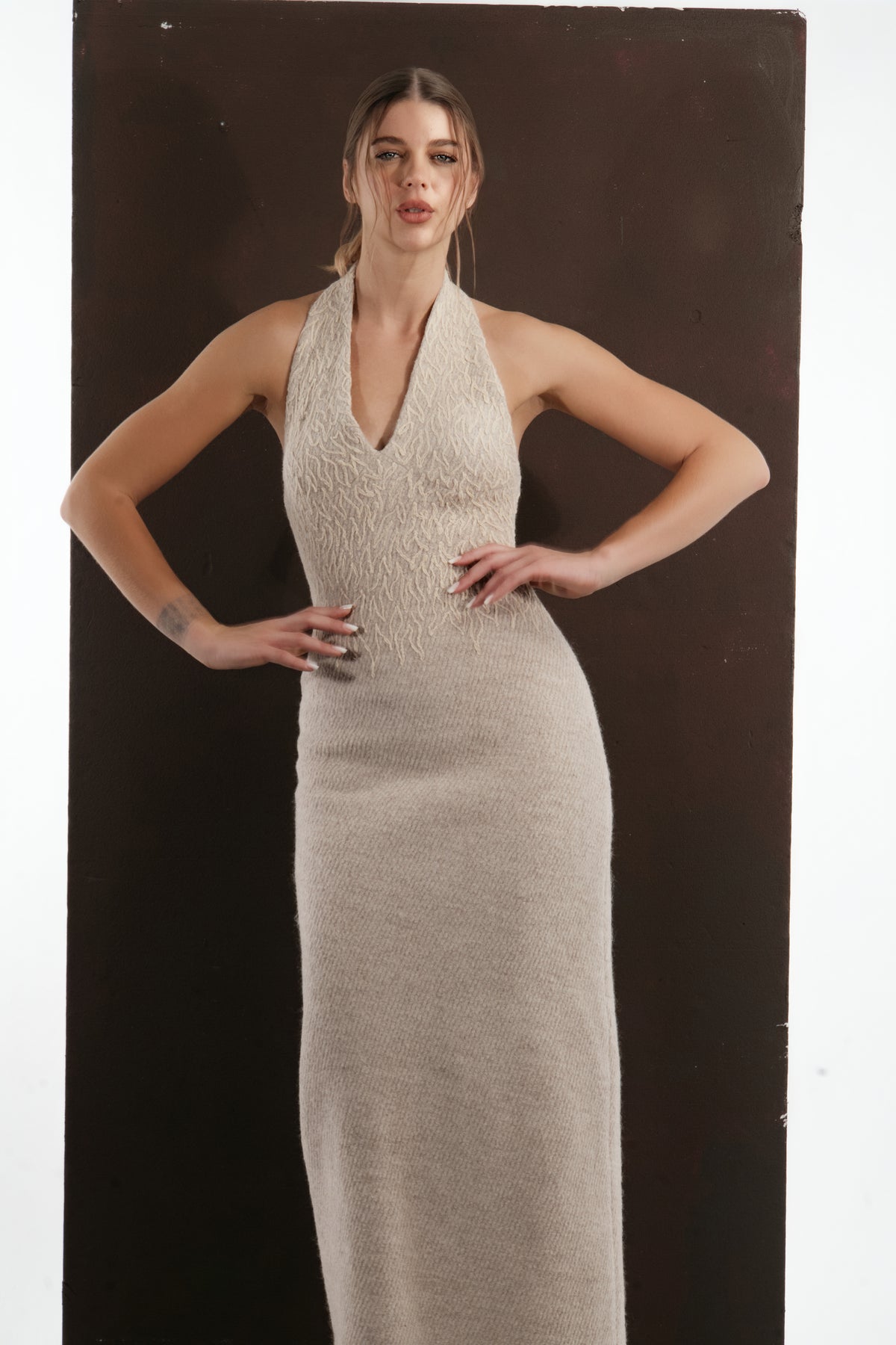 ALISADUDAJ beige wool halterneck column dress, front view with hands on hips showing bodice texture
