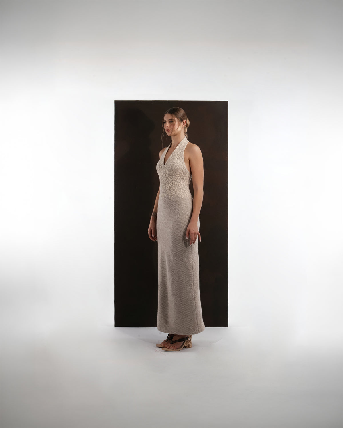 ALISADUDAJ beige wool halterneck column dress, side three-quarter view showing slim column silhouette