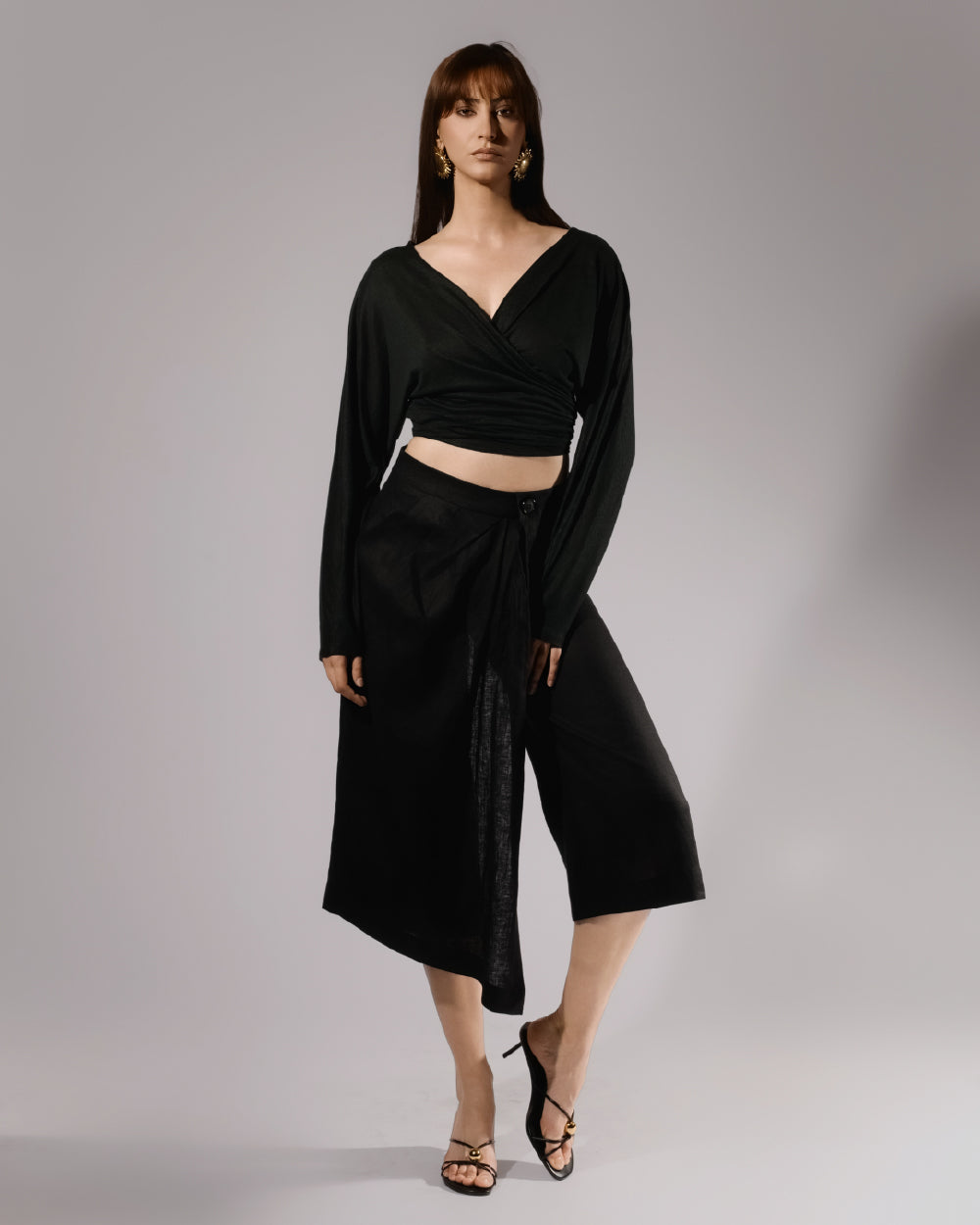 ALISADUDAJ black linen deep-V wrap top and midi skirt set, front three-quarter view showing crossover neckline and buttoned wrap waist