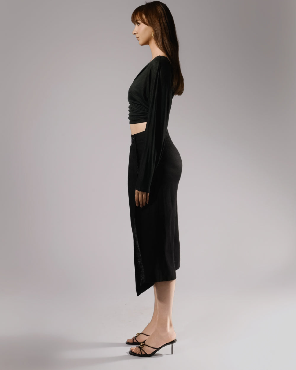 ALISADUDAJ black linen deep-V wrap top and midi skirt set, side profile showing draped sleeve and side slit