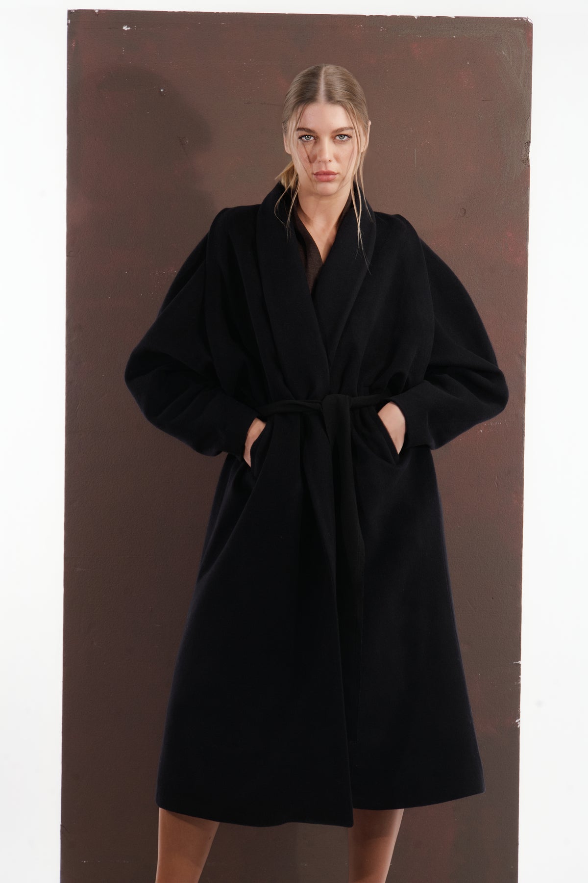 ALISADUDAJ black wool belted wrap coat, front view with hands in pockets showing shawl collar
