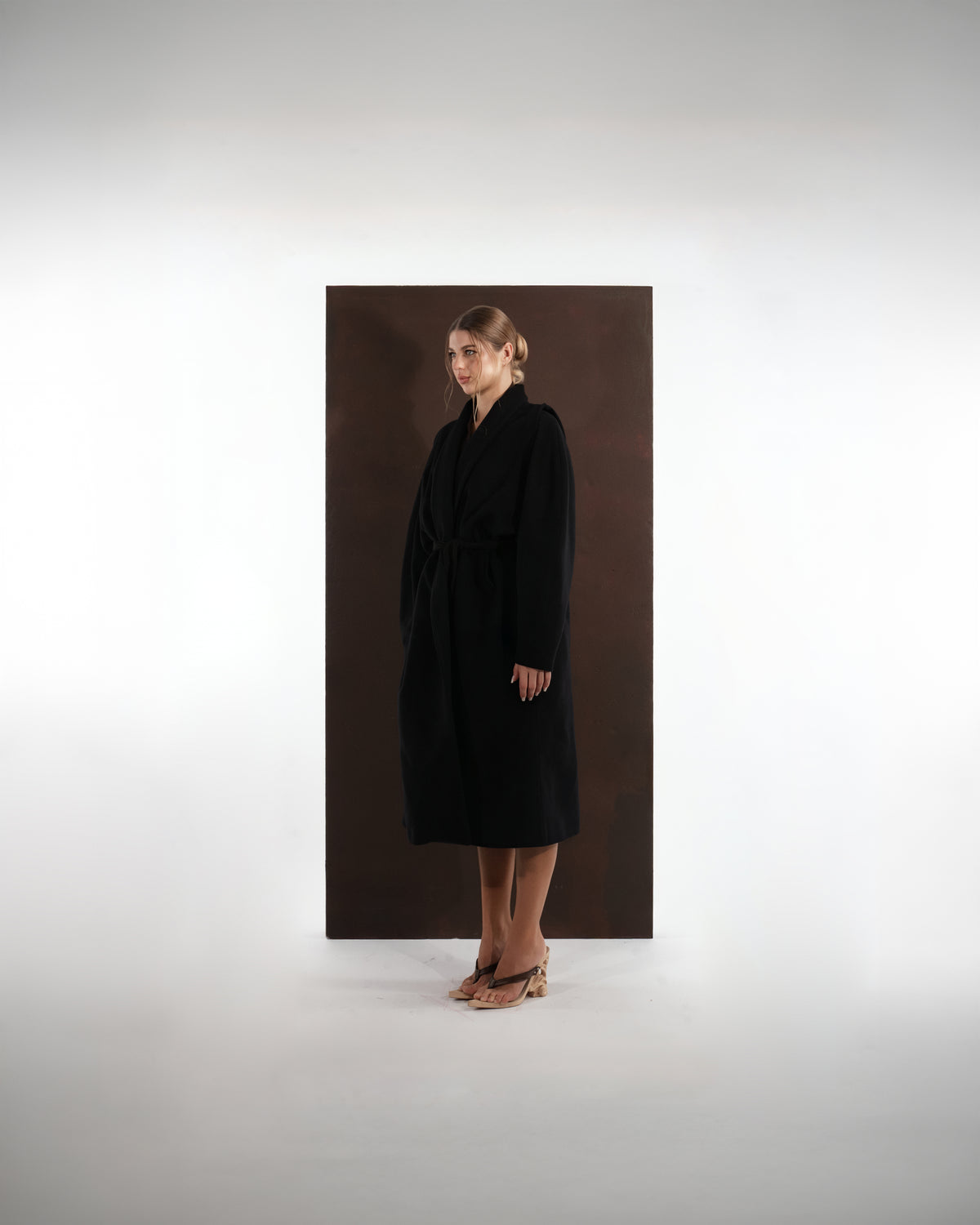 ALISADUDAJ black wool belted wrap coat, side three-quarter view showing wrap front and tie belt