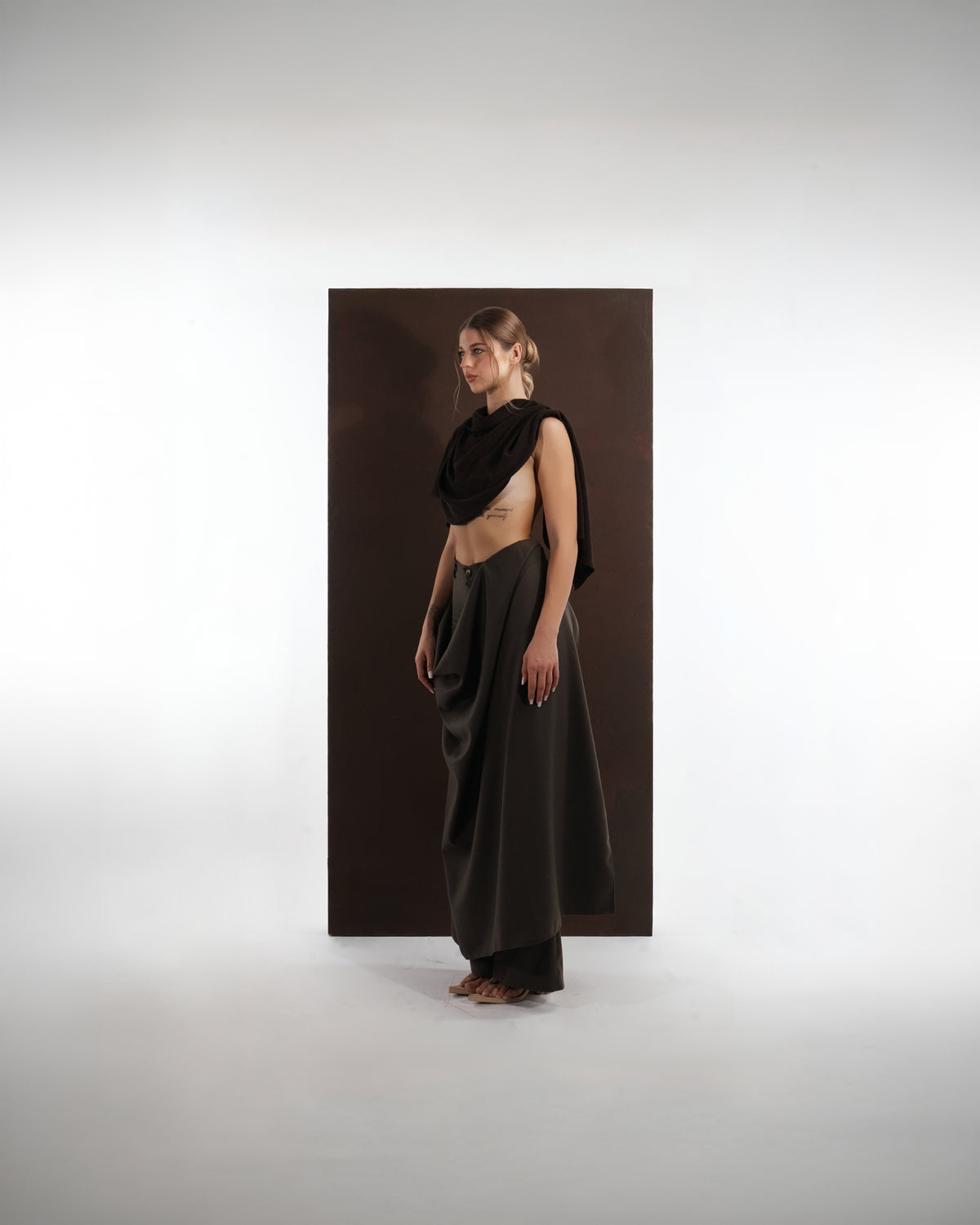 ALISADUDAJ black wool draped cowl top and trouser set, side profile showing cowl drape and wide-leg trousers