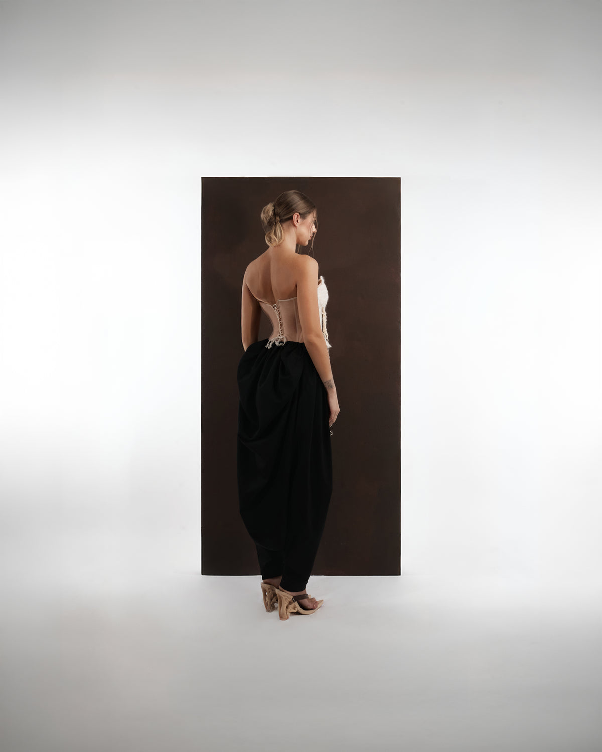 ALISADUDAJ black wool draped harem trousers, back view showing gathered drape and tapered ankle