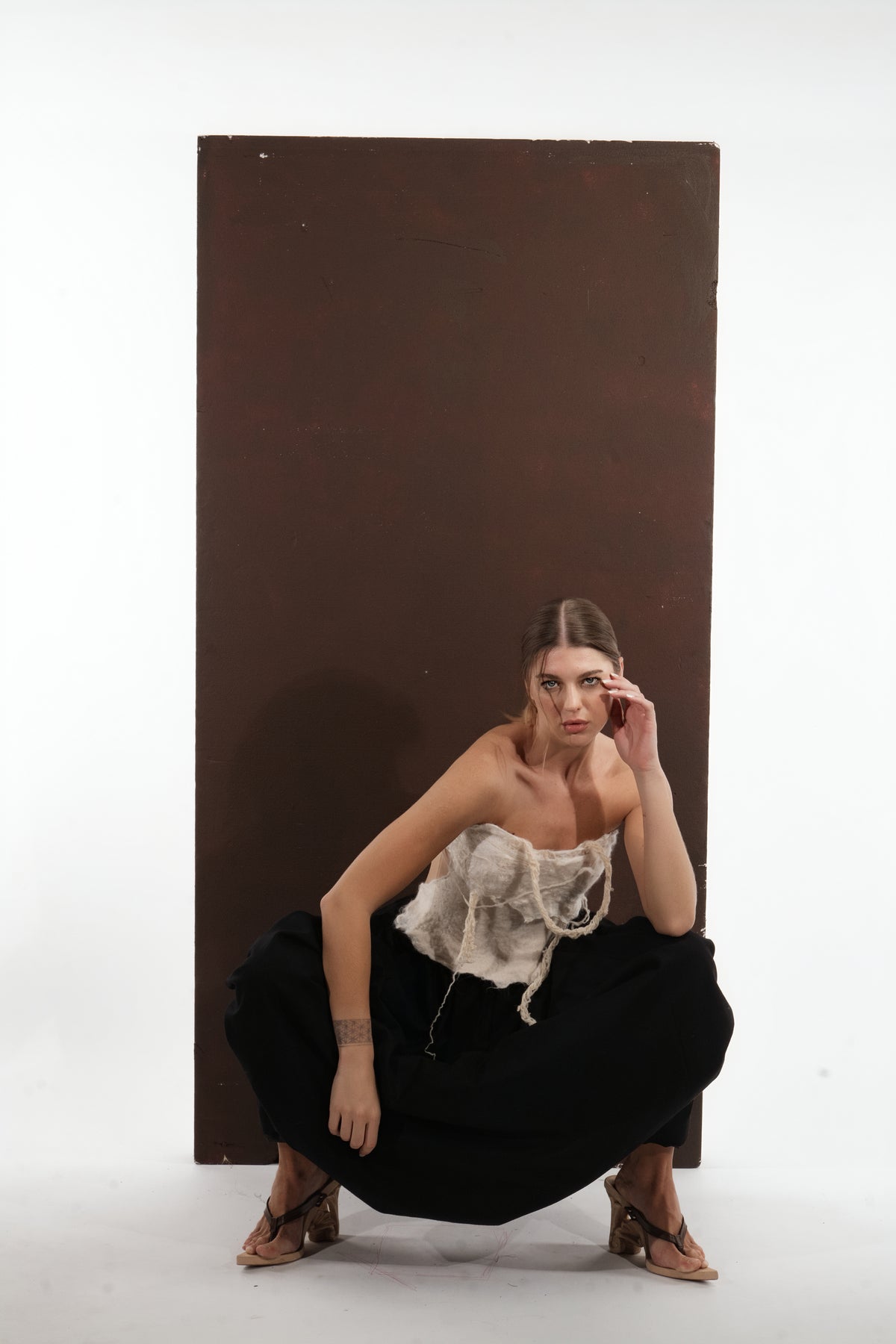 ALISADUDAJ black wool draped harem trousers, crouching side view showing gathered volume