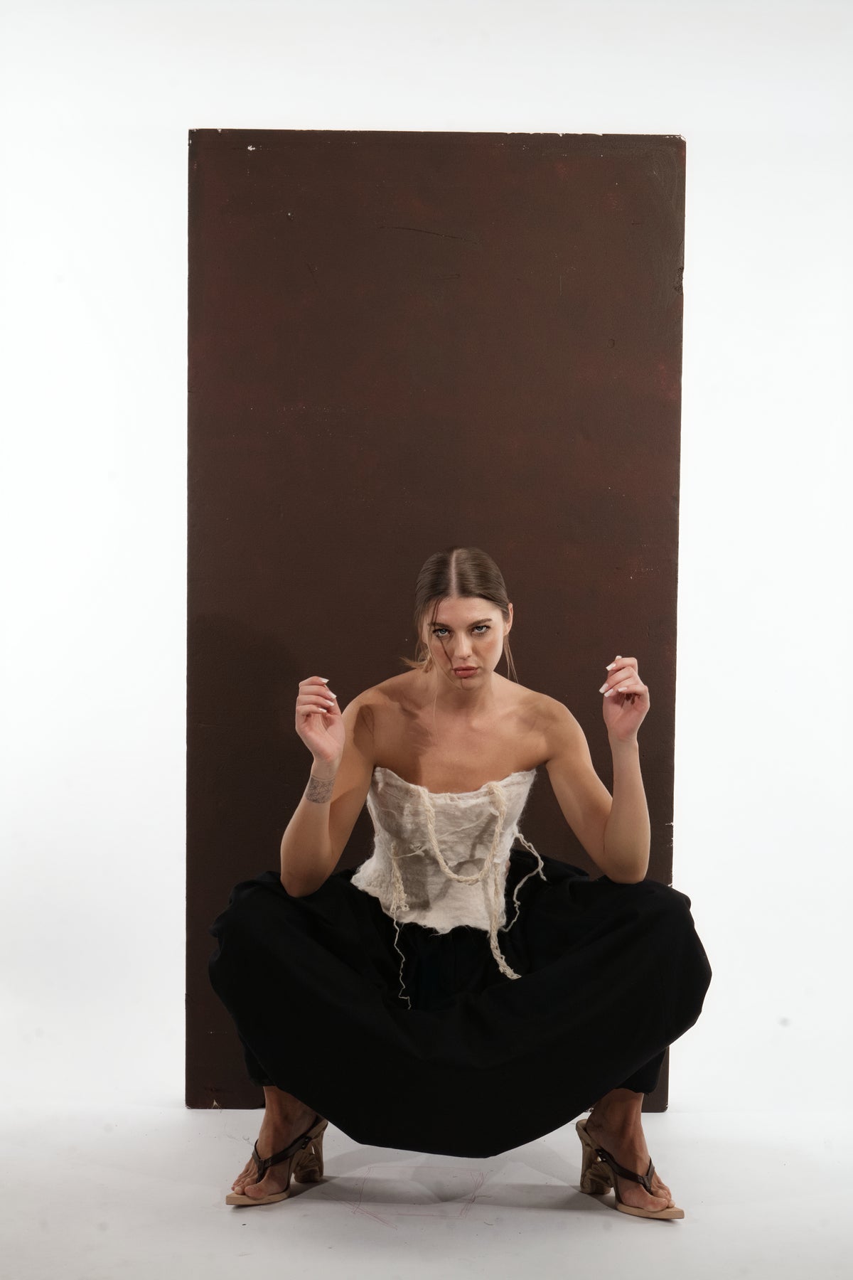 ALISADUDAJ black wool draped harem trousers, crouching view showing draped folds across the legs