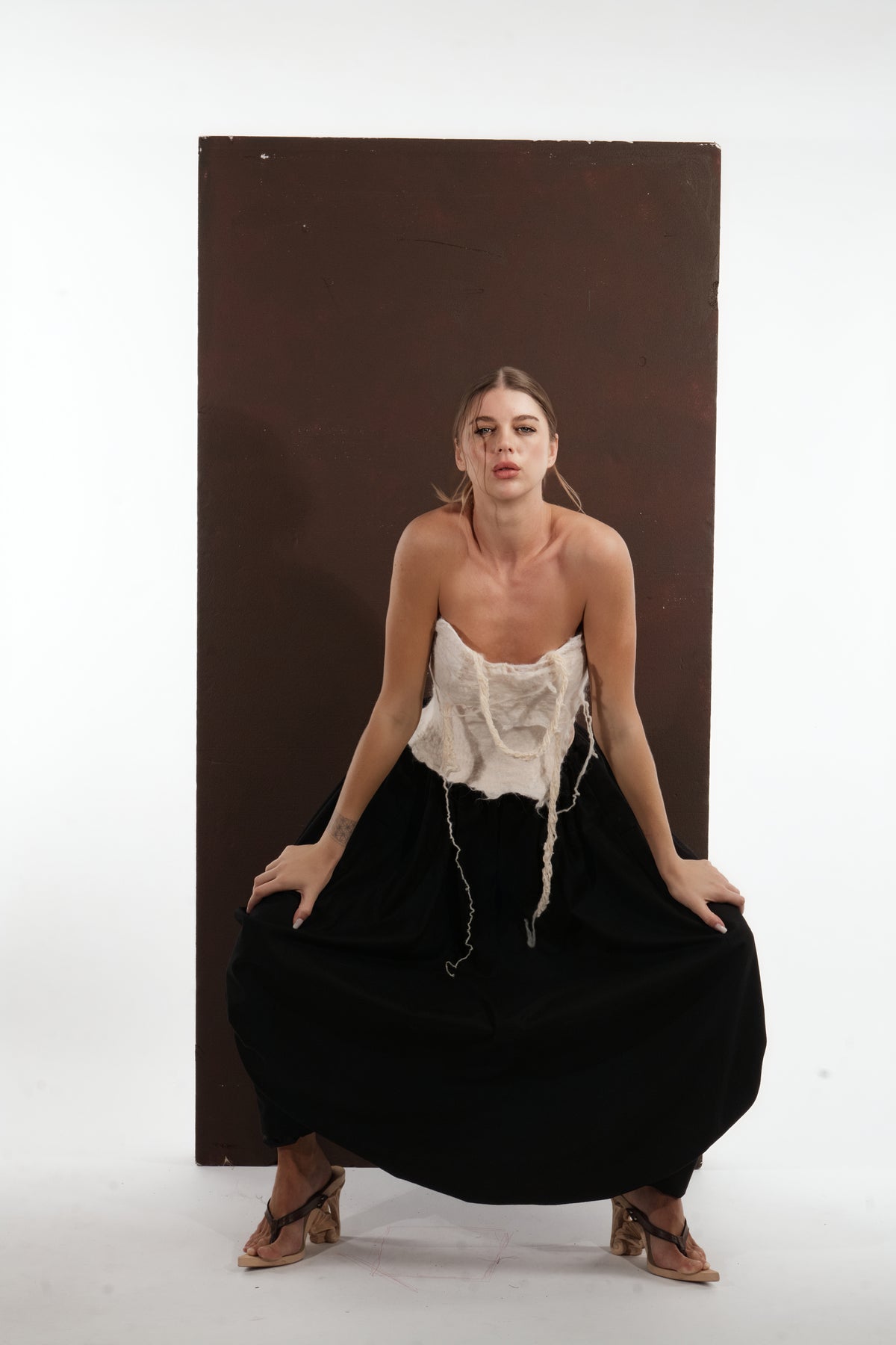 ALISADUDAJ black wool draped harem trousers, crouching front view showing waist and draped legs