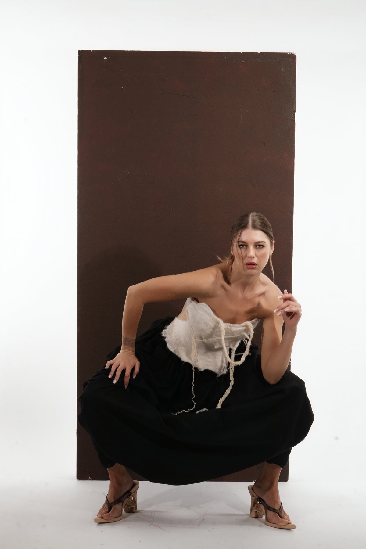 ALISADUDAJ black wool draped harem trousers, three-quarter crouching view showing fabric volume