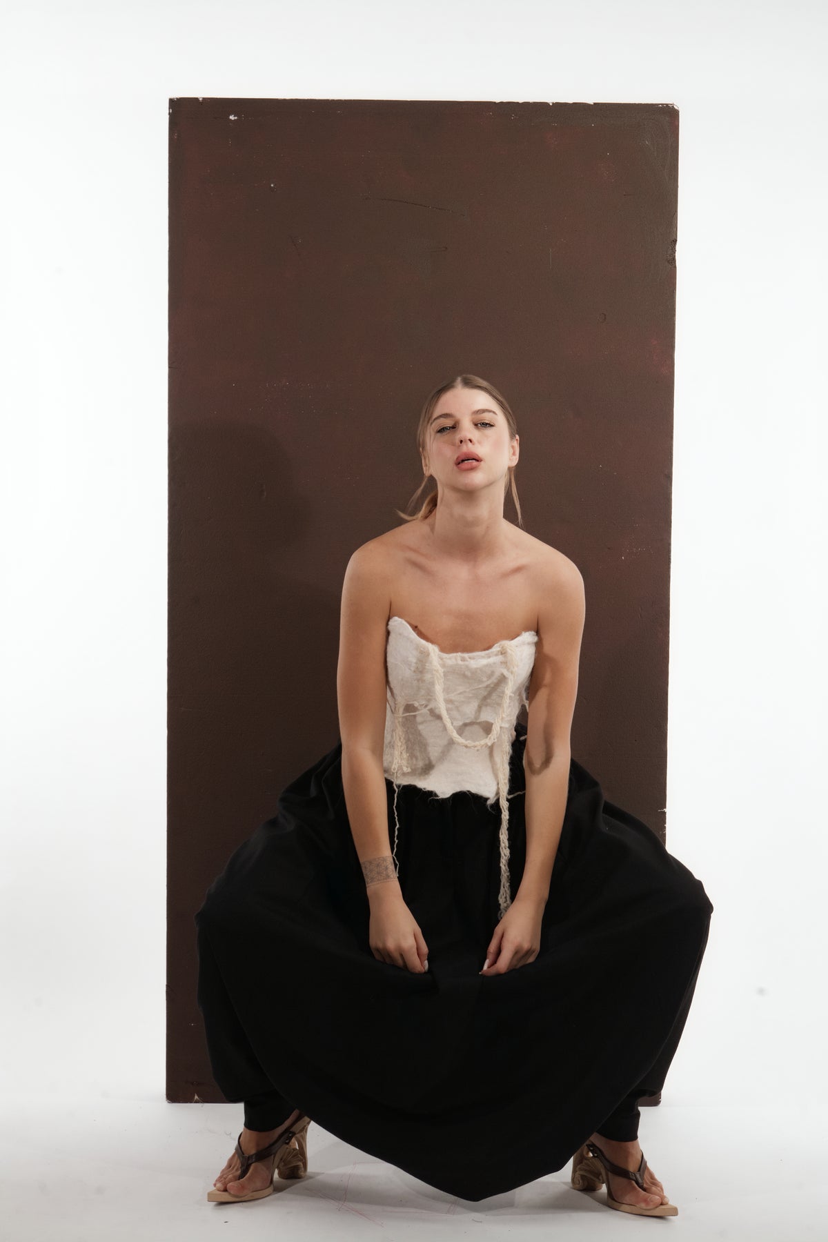 ALISADUDAJ black wool draped harem trousers, crouching front view showing full width of the drape