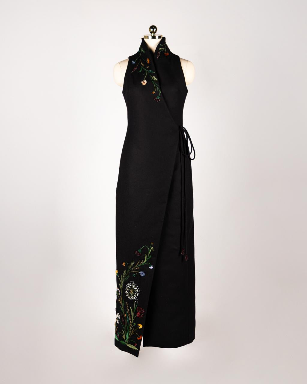 ALISADUDAJ black wool hand-embroidered wrap dress on a mannequin, front view, full length, showing floral embroidery at collar and hem