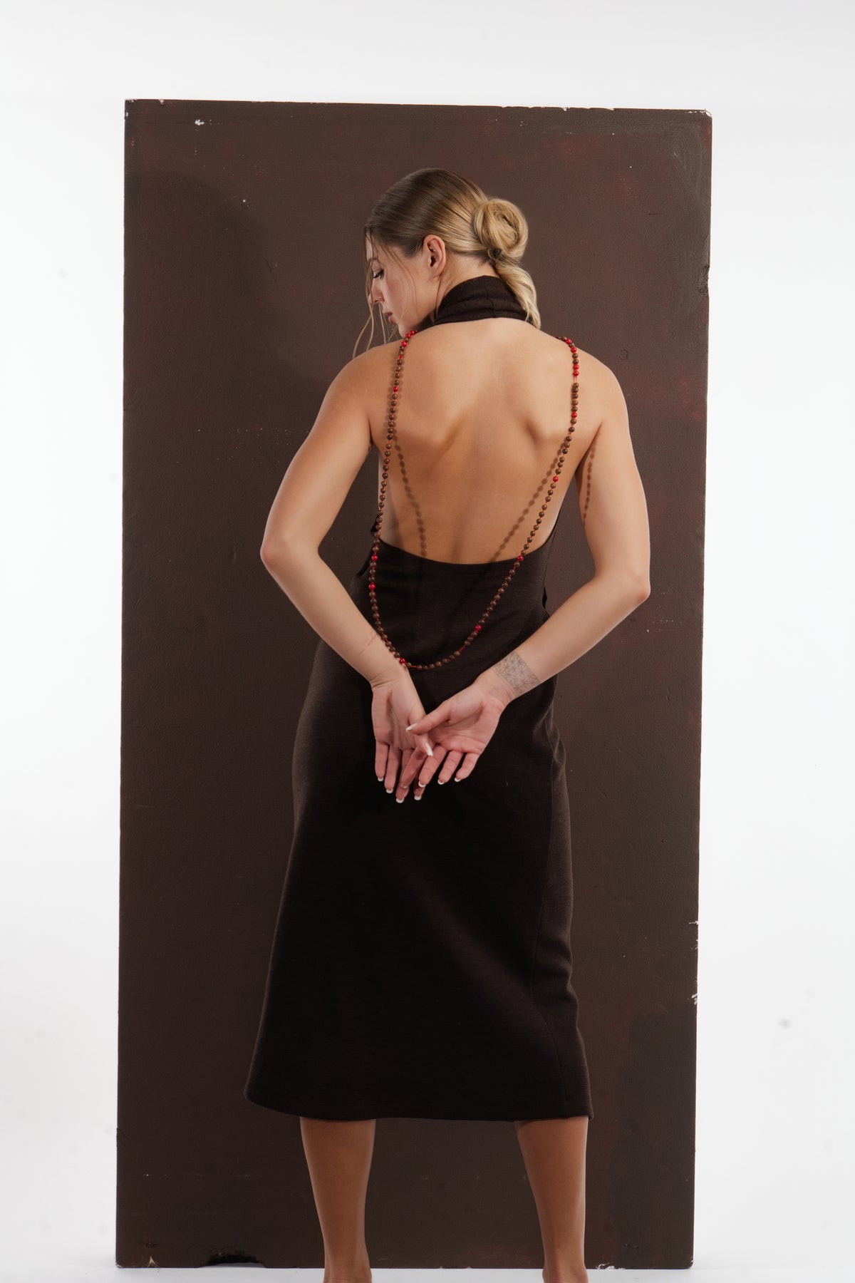ALISADUDAJ brown wool garden-embroidered wrap dress, back view with hands clasped showing beaded halter strap, wool blend