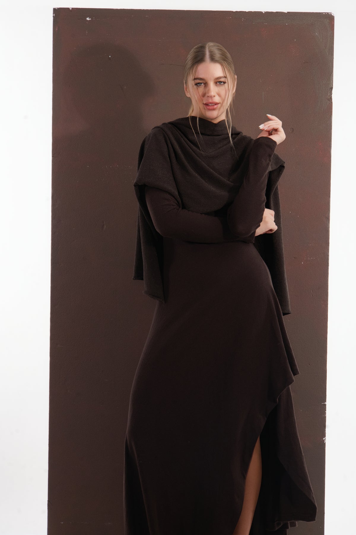 ALISADUDAJ brown wool open-back maxi dress, front three-quarter view with shawl and hand raised, showing slit