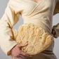 ALISADUDAJ Çantro beige resin crochet clutch bag held at the waist of the CRAFT 08 off-white wool wrap outfit, close-up