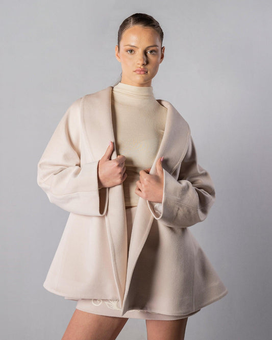 ALISADUDAJ CRAFT 01 beige cashmere coat and embroidered mini skirt set, front view holding coat open showing shawl collar