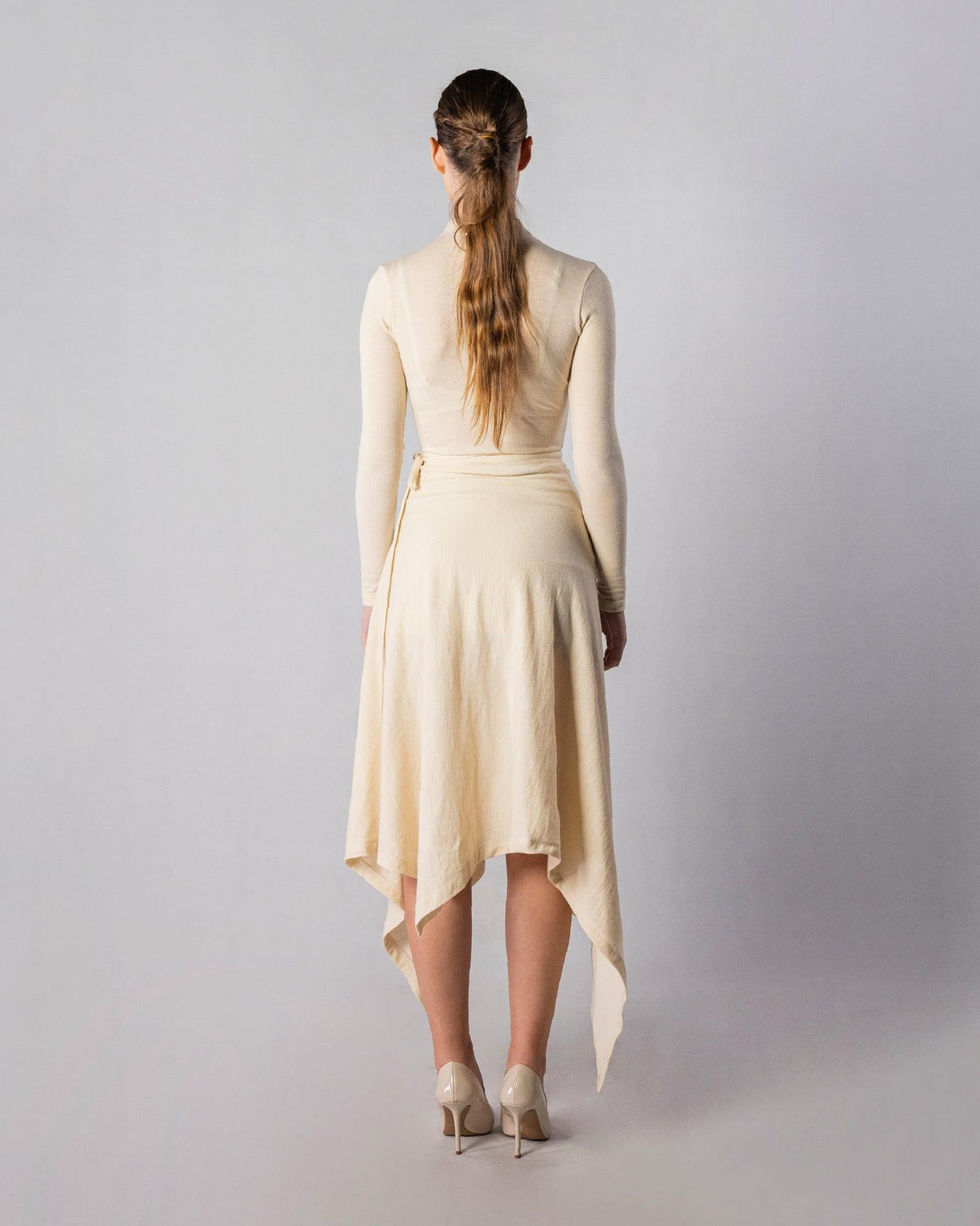 ALISADUDAJ CRAFT 07 off-white wool turtleneck and wrap skirt set, back view showing pointed handkerchief hem, wool