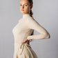 ALISADUDAJ CRAFT 07 off-white wool turtleneck and wrap skirt set, side three-quarter view with hand at the waist tie
