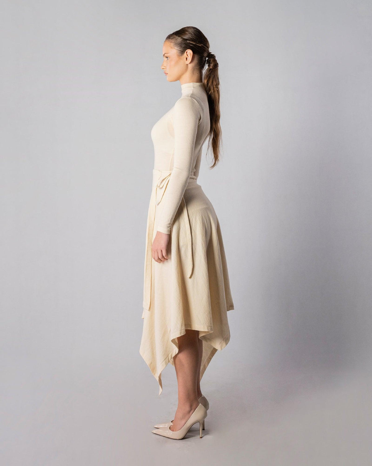 ALISADUDAJ CRAFT 07 off-white wool turtleneck and wrap skirt set, side profile showing handkerchief hem