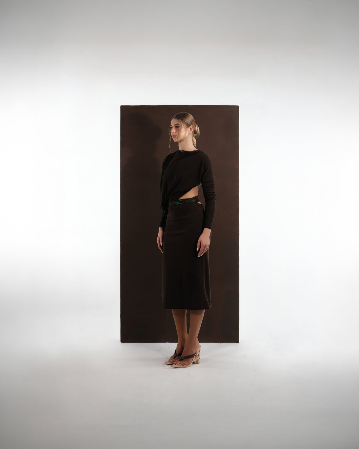 ALISADUDAJ dark brown wool draped set, front three-quarter view showing waist cut-out and green floral embroidery