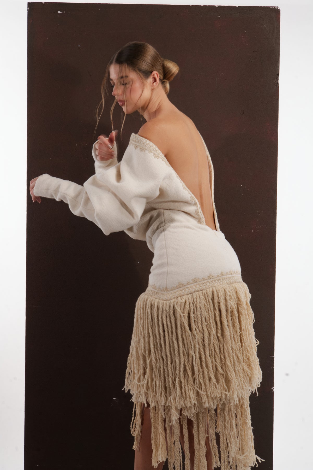 ALISADUDAJ ivory wool fringed dress, back view with arm extended showing blouson sleeve and fringe