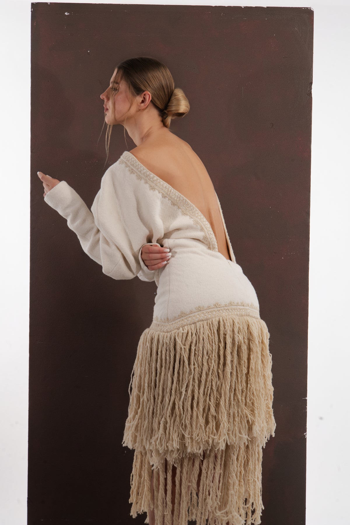 ALISADUDAJ ivory wool fringed dress, profile view showing open back, braid trim and tiered fringe skirt