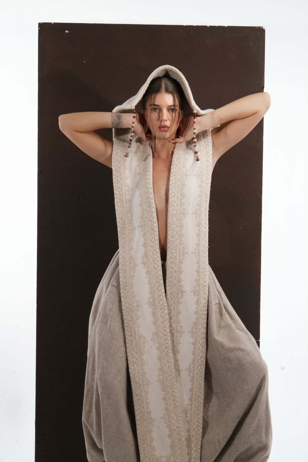 ALISADUDAJ ivory wool beaded hooded vest, front close-up with hood up and hands behind neck