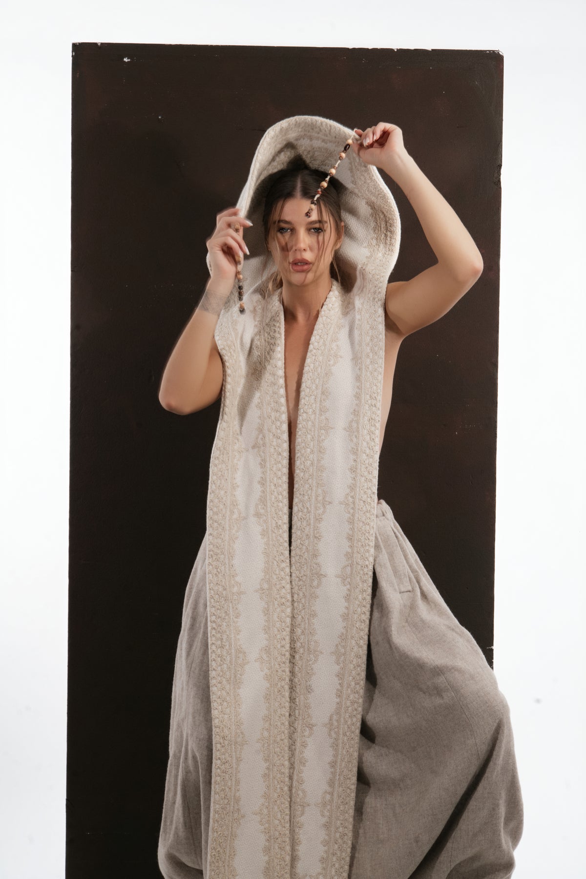 ALISADUDAJ ivory wool beaded hooded vest, close-up of jacquard-patterned hood held open with one hand
