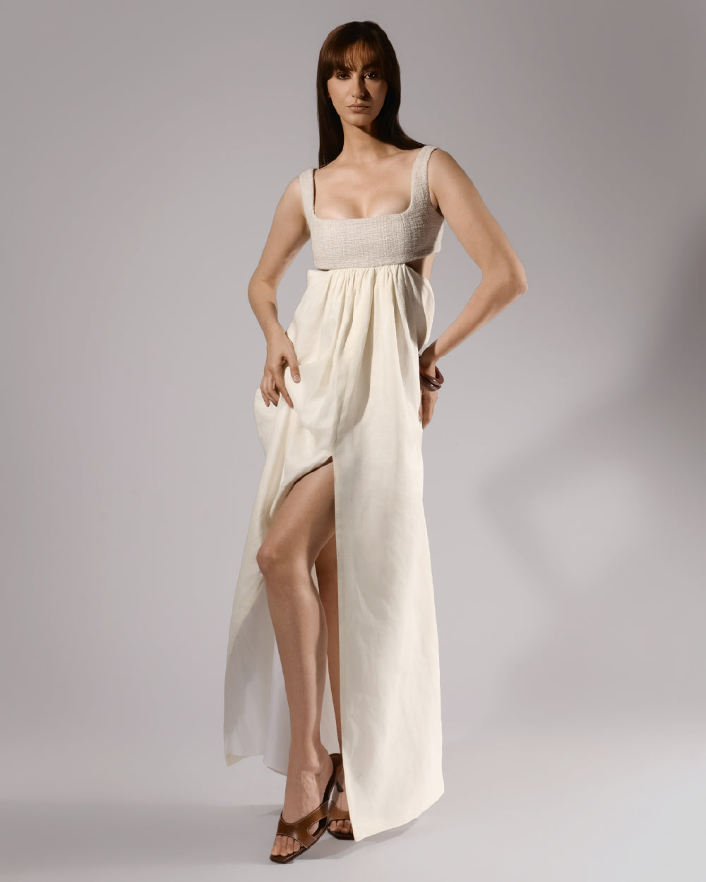 ALISADUDAJ ivory linen empire-waist gown, front view with hand on hip showing high front slit