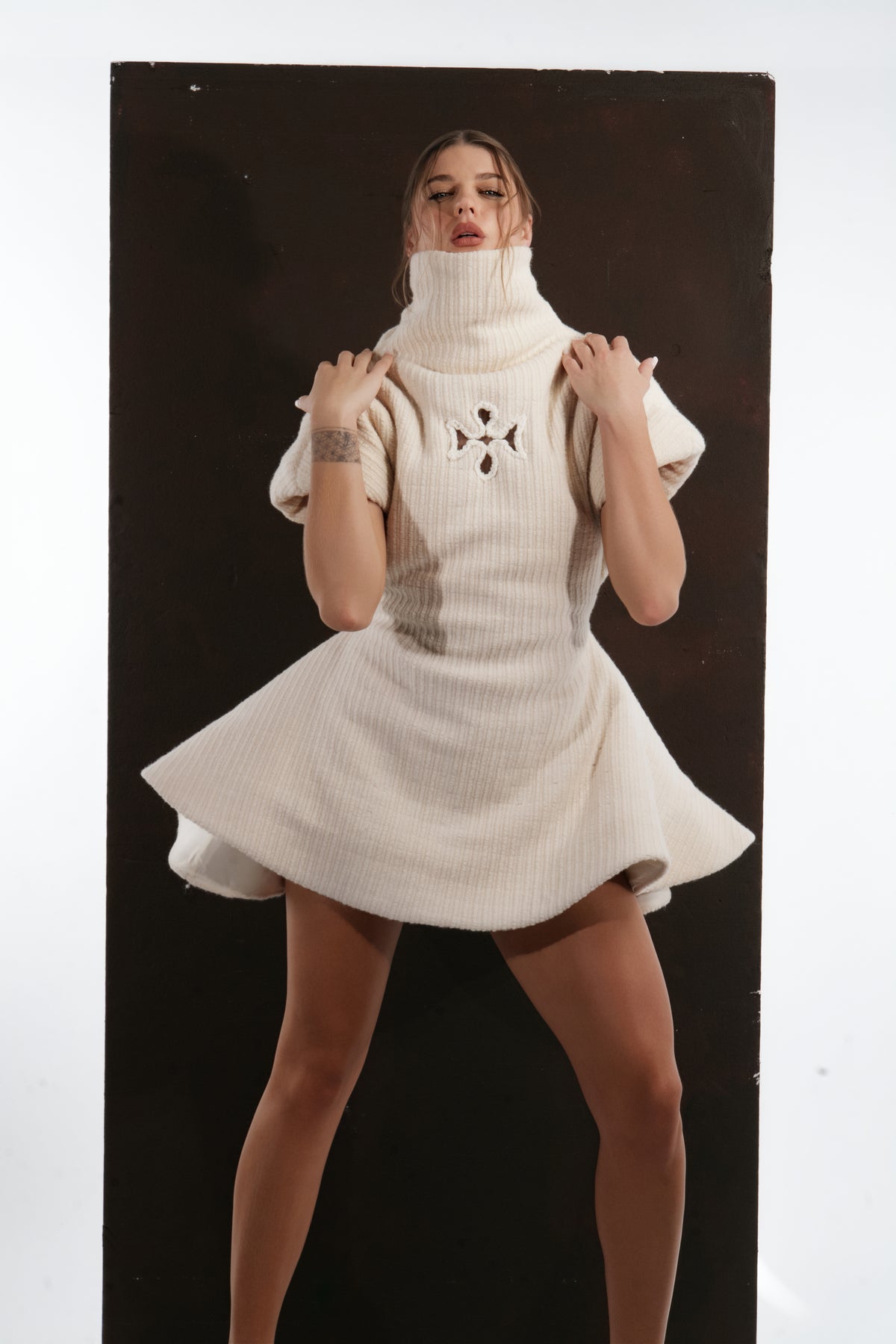 ALISADUDAJ ivory ribbed wool flared mini dress, front view with hands at the collar showing turtleneck