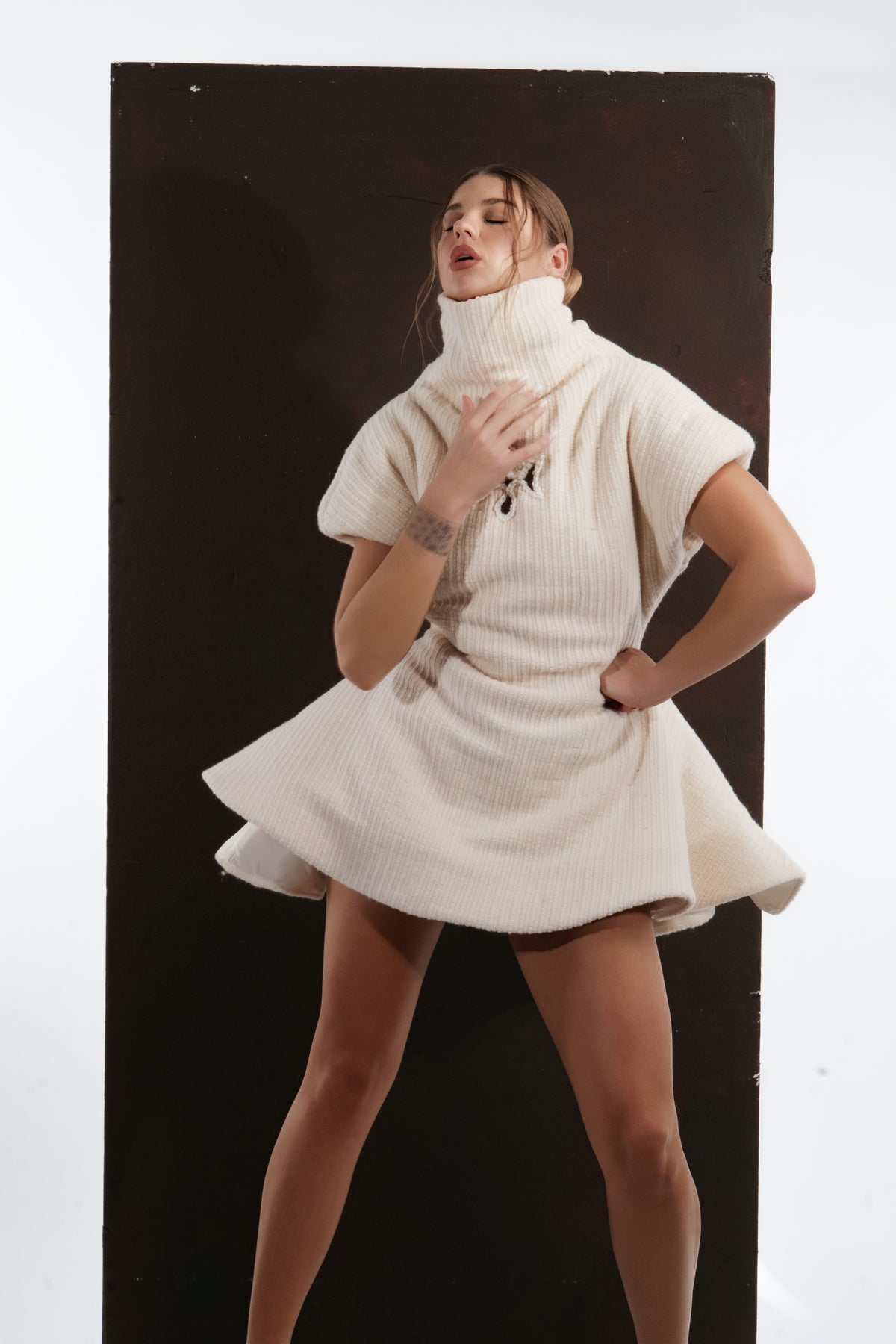 ALISADUDAJ ivory ribbed wool flared mini dress, three-quarter view in movement showing skirt flare
