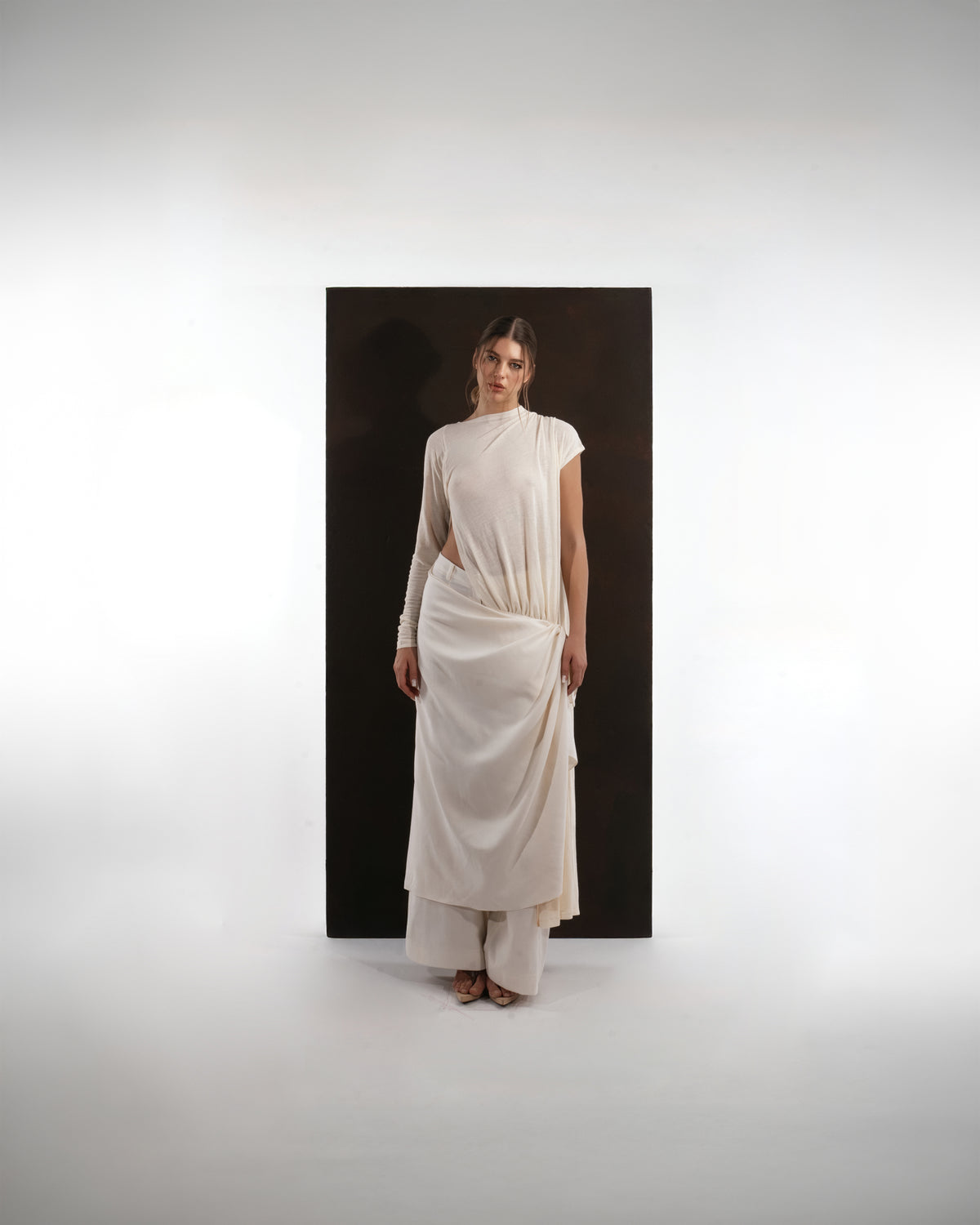 ALISADUDAJ ivory wool draped asymmetric set, front three-quarter view showing side cut-out and draped wrap skirt