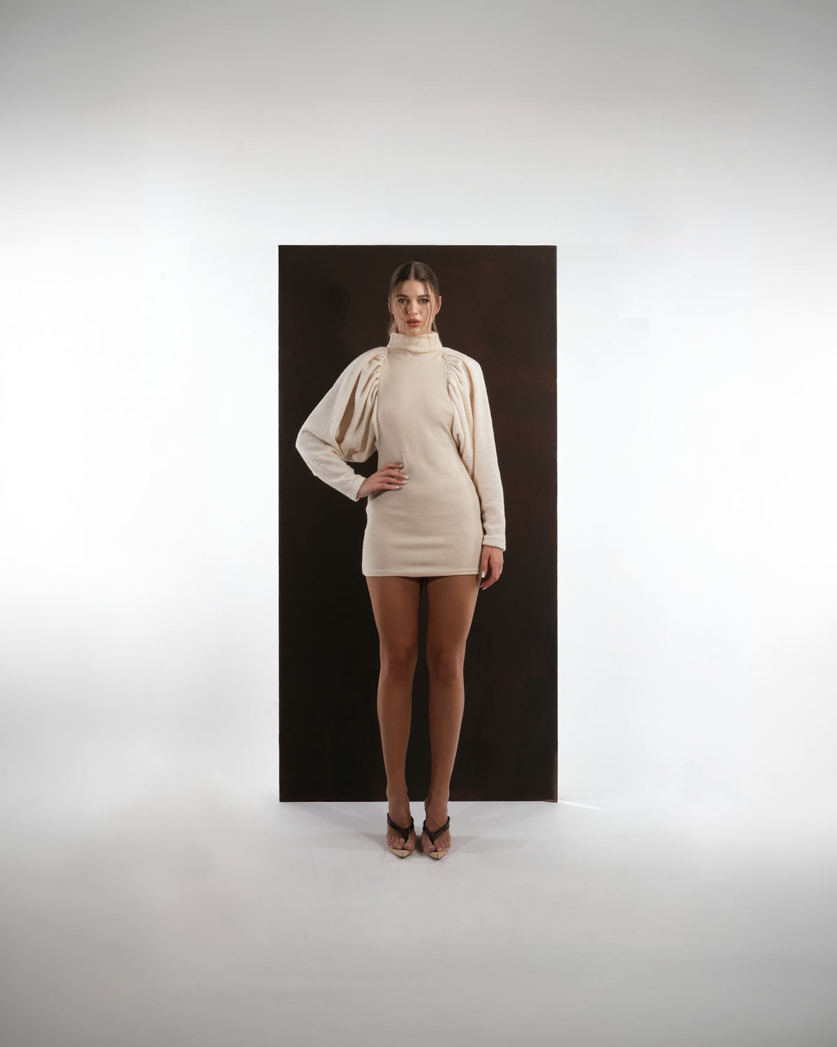 ALISADUDAJ ivory wool draped mini dress, front view with one hand on hip showing draped shoulder