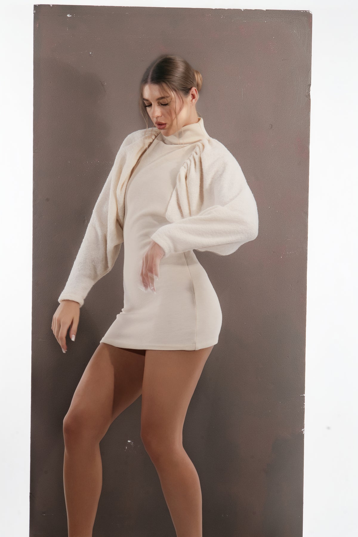 ALISADUDAJ ivory wool draped mini dress, three-quarter view in movement showing sleeve drape