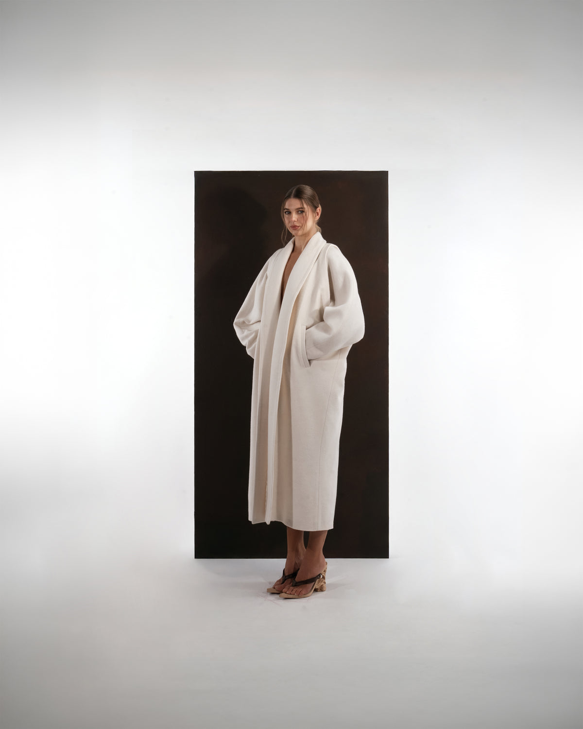 ALISADUDAJ ivory wool cocoon coat, three-quarter view with hands in pockets showing coat drape