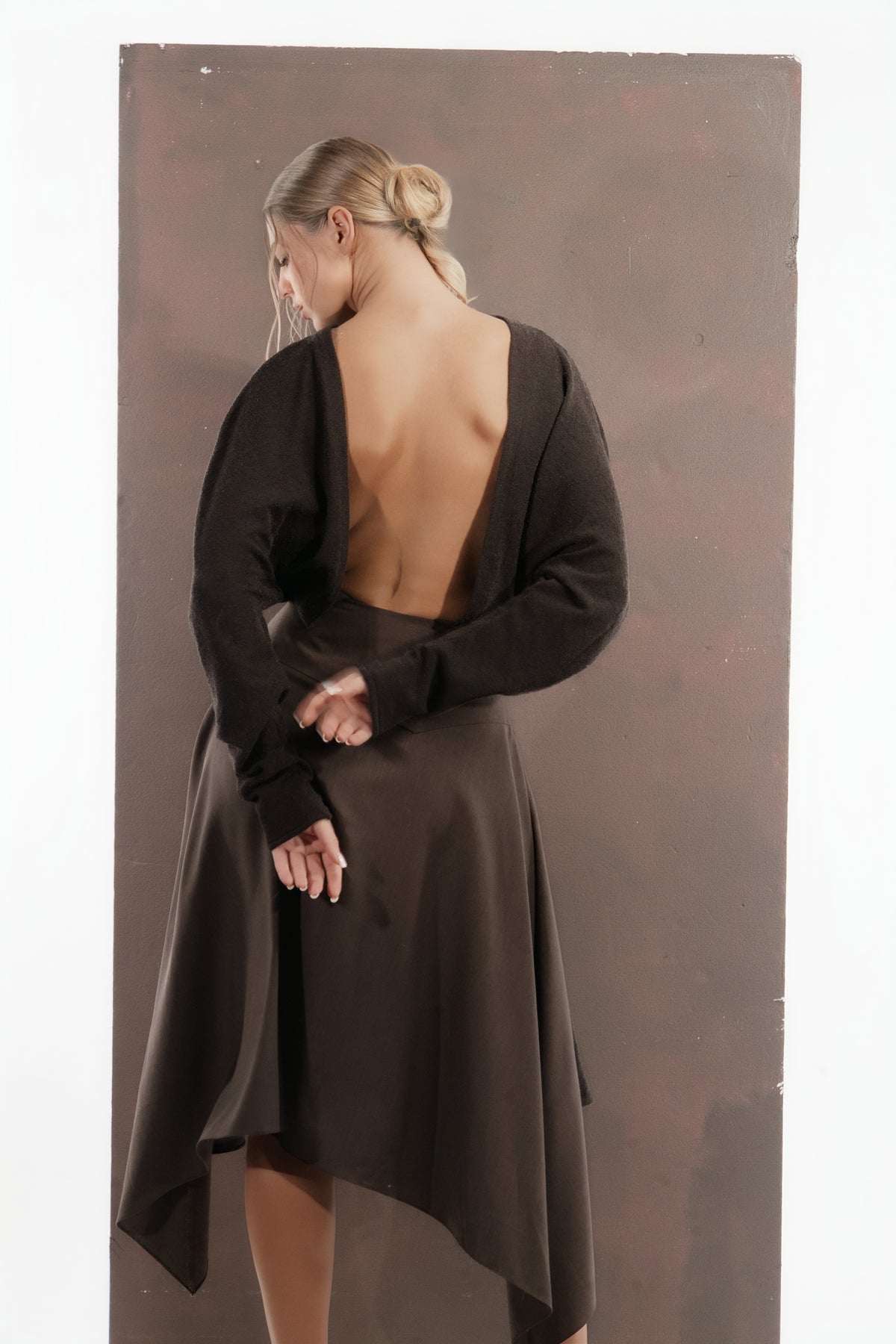 ALISADUDAJ mocha brown wool open-back dress, back view with hands behind the waist showing open back