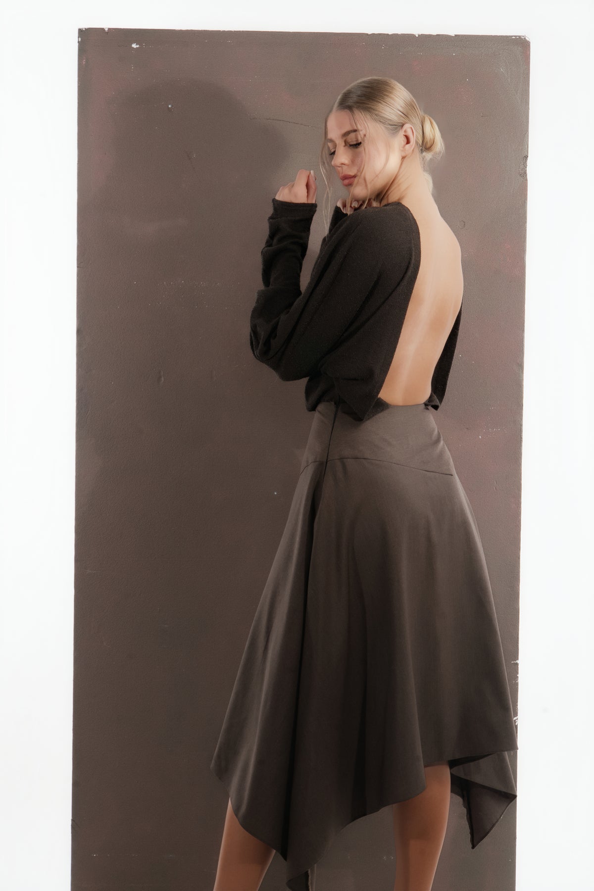 ALISADUDAJ mocha brown wool open-back dress, back three-quarter view with hand at the shoulder