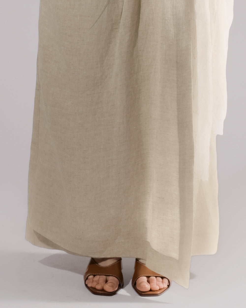 ALISADUDAJ taupe linen wide-leg trousers, close-up of hem and sheer overlay falling over sandals