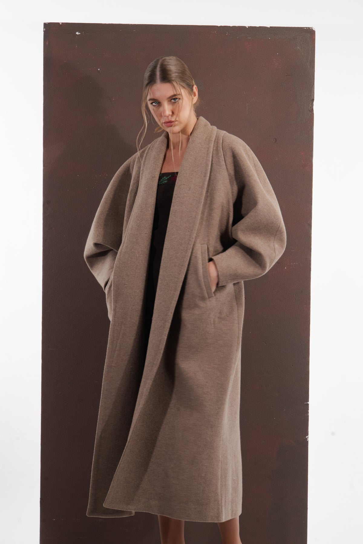 ALISADUDAJ taupe wool oversized coat, three-quarter view with hands in pockets showing coat drape