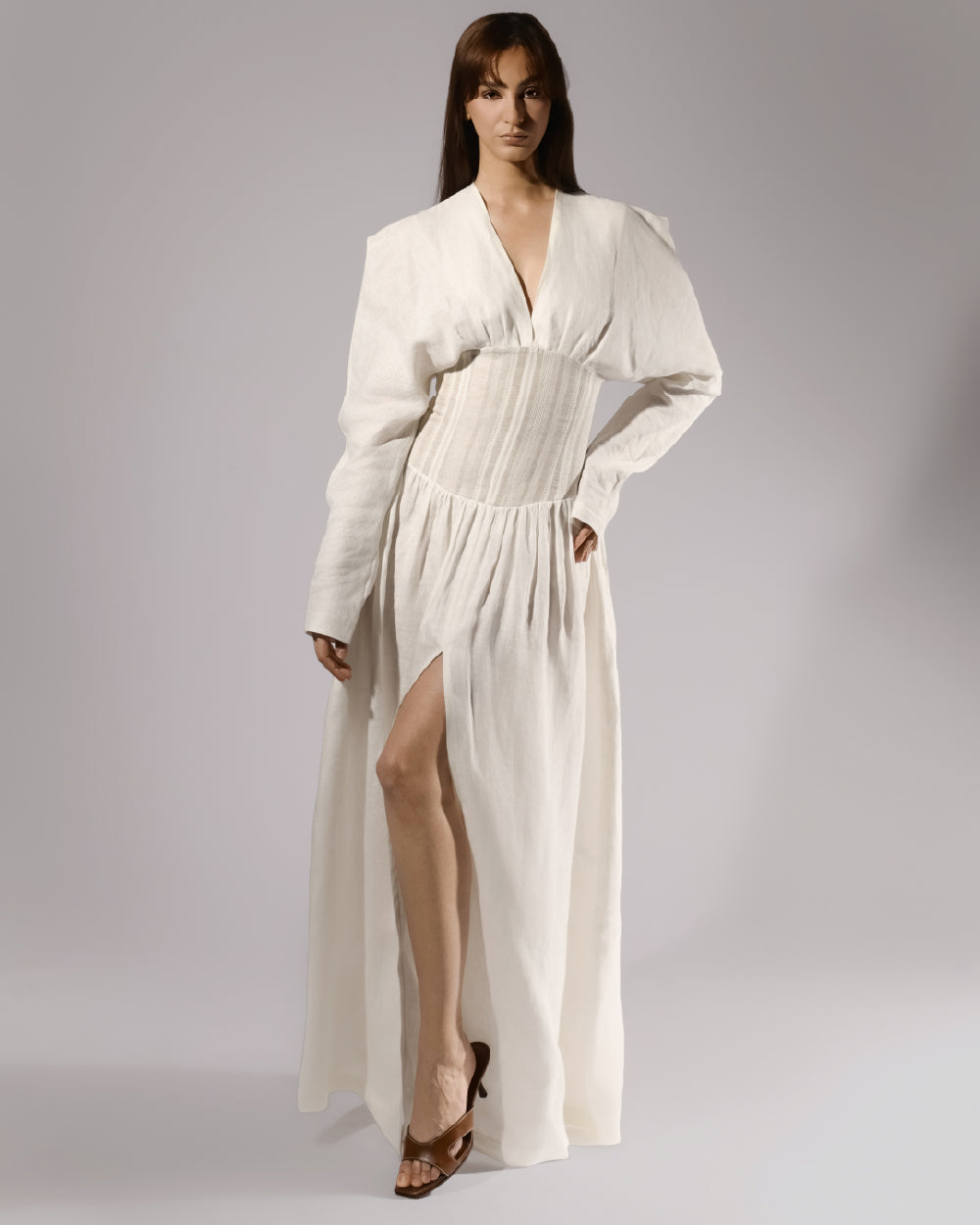 ALISADUDAJ white linen corseted maxi dress, front three-quarter view with hand on hip showing high leg slit