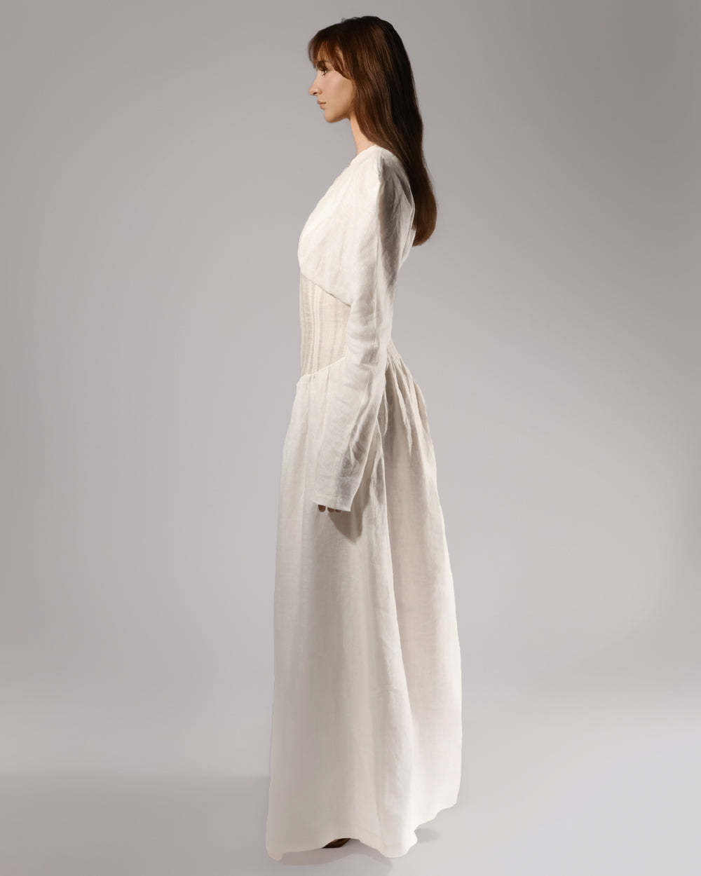 ALISADUDAJ white linen corseted maxi dress, side profile showing structured shoulders and long sleeves