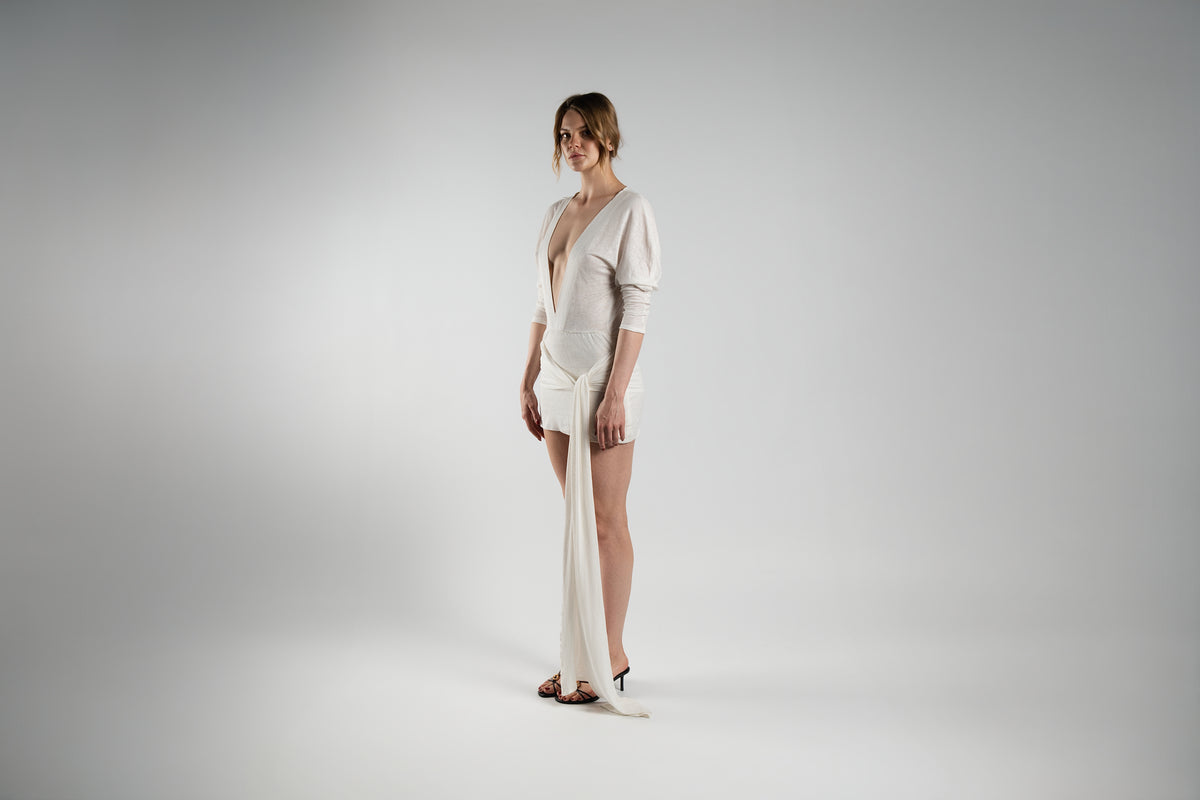 ALISADUDAJ white linen plunge-neck mini dress, front three-quarter view showing draped bodice and sash