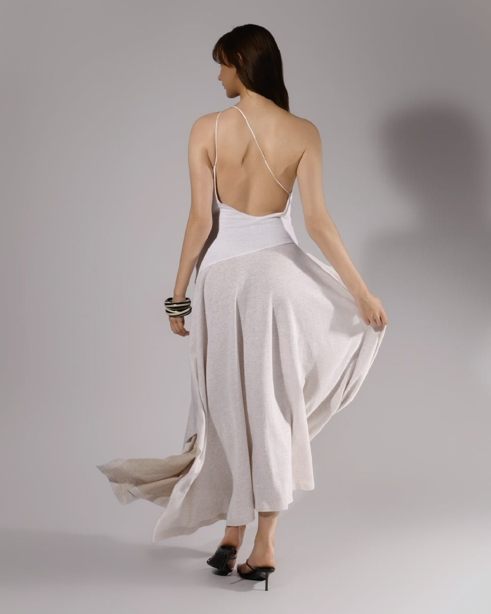 ALISADUDAJ white linen strappy maxi dress, back three-quarter view holding the skirt out to show volume